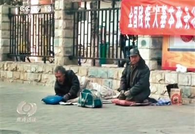 工人體育場(chǎng)北路，兩位乞討者路邊乞討，并輪流扮成“病人”（躺地者）。 央視截圖