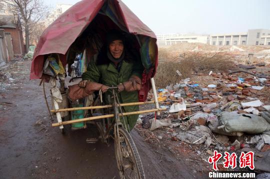 圖為老人走出窩棚，推著三輪車準備出去撿拾廢品。周小云 攝